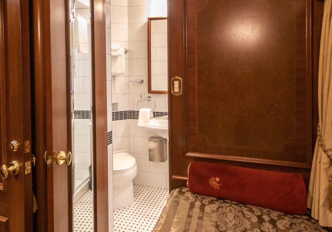 A queen bed in a train car, with accompanying bathroom